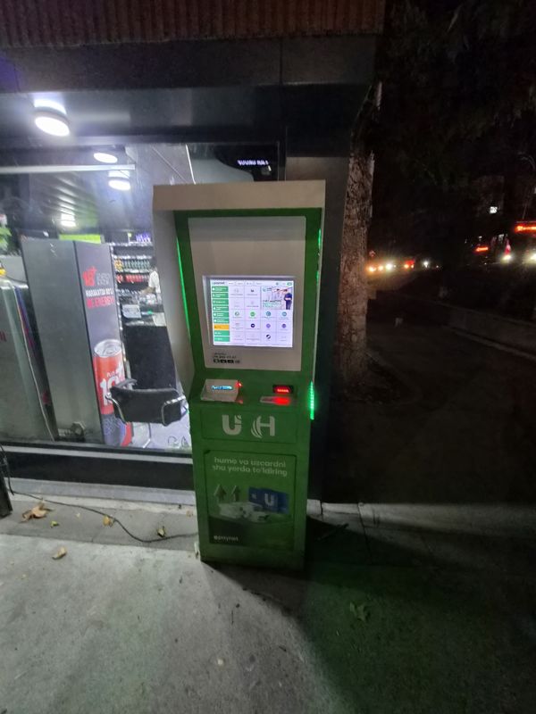 Терминал Paynet вечером у витрины магазина: пополнение карт Humo и Uzcard («humo va uzcardni shu yerda to'ldiring»)