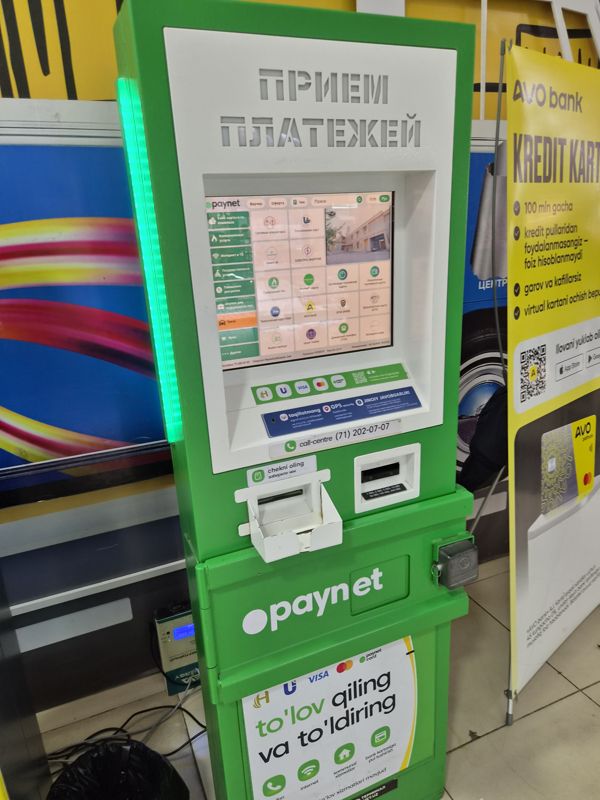 Терминал Paynet «Приём платежей» в Экобазаре; рядом — стенд AVO bank с рекламой кредитной карты