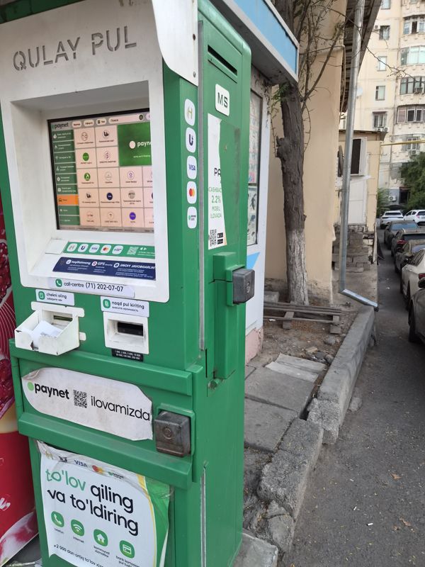 Уличный терминал Paynet «Qulay pul» на тротуаре у киоска во дворе: оплата и пополнение («to'lov qiling va to'ldiring»), карты Humo, Uzcard, Visa, Mastercard, call-центр (71) 202-07-07