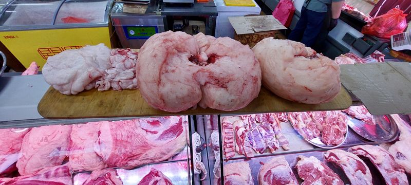 На разделочной доске над витриной лежат крупные куски жира; в витрине баранина и говядина