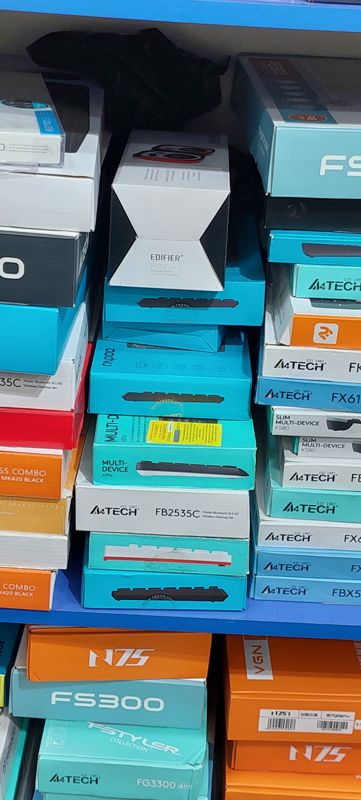 Полка с коробками клавиатур и комплектов: A4Tech Fstyler, Rapoo, Logitech K375s, 2E, VGN N75; сверху колонки Edifier R12U