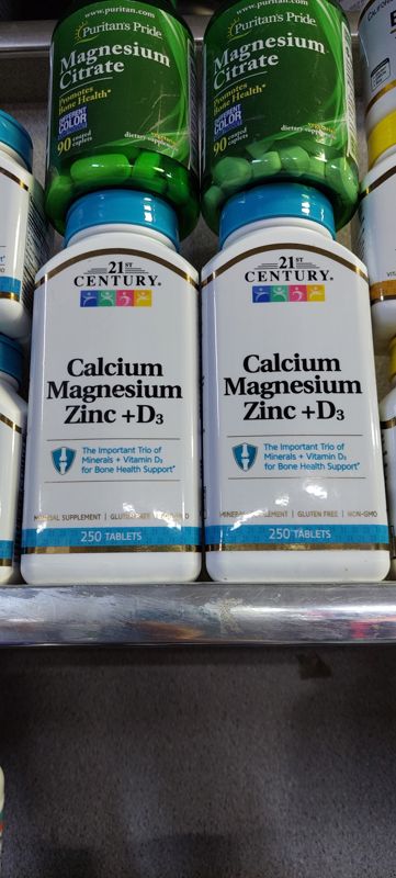 Две банки 21st Century Calcium Magnesium Zinc + D3 (250 таблеток) на полке, сверху Puritan's Pride Magnesium Citrate