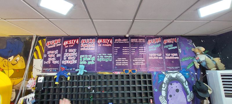 Стена с плакатами акций и прайс-листами (рус. и узб.) за стойкой батутного центра, шкафчики для обуви