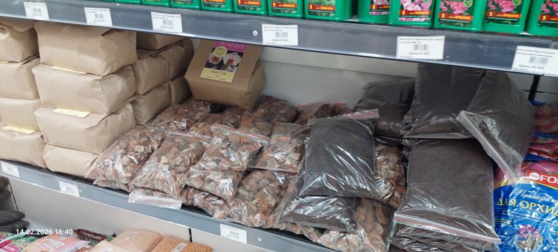 Нижняя полка с грунтами: бумажные пакеты кусковой коры для орхидей «Чистая кора» (фракция 12-18 мм, 2 литра), прозрачные пакеты красноватой коры и тёмного грунта, справа синие мешки Bona Forte для орхидей; сверху ряд ценников Bona Forte