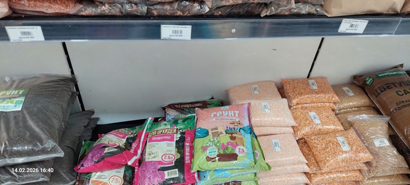 Нижние полки с грунтами и керамическими гранулами: мешки почвогрунта Азбука Роста для орхидей 2,5 л, грунт с биогумусом для комнатных цветов Магия Роста 2,5 л, фасованные в пакеты оранжевые и бежевые гранулы, коричневый мешок ионитного субстрата «Цветущий сад», слева мешки тёмного грунта; сверху три ценника