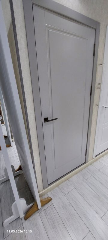 Образец межкомнатной двери светло-серого цвета с гладким полотном и тёмной ручкой на розетке
