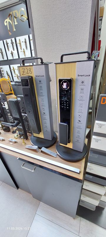 Витрина: два образца умных замков Smart Lock на подставках, врезные электронные замки, дверные ручки, стопоры, справа стенд Döllken
