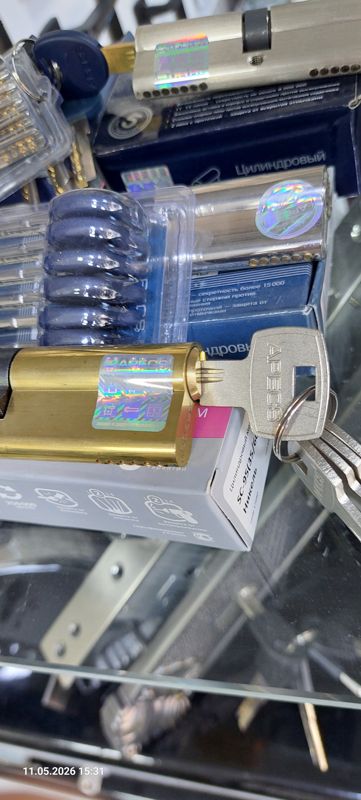 Витрина со стеклянными полками: цилиндровые механизмы замков Apecs в коробках с голографическими наклейками, ключи