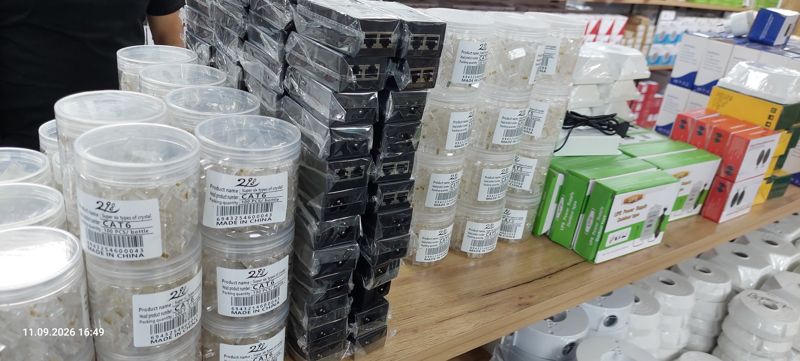 Банки с разъёмами RJ45 CAT6 и CAT5 (по 100 шт), чёрные устройства с портами RJ45 в плёнке, зелёные коробки UPS Power Supply, монтажные коробки
