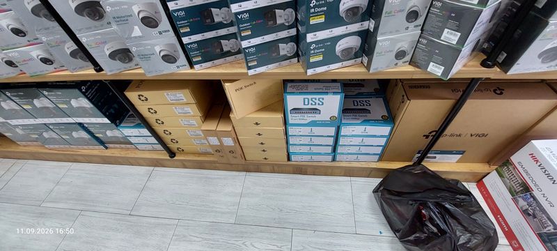 Нижняя полка: коробки DSS Smart POE Switch на 10 портов (100 Мбит/с), безымянные коробки POE Switch, сверху камеры VIGI IR Dome; справа край коробки Hikvision Embedded NVR