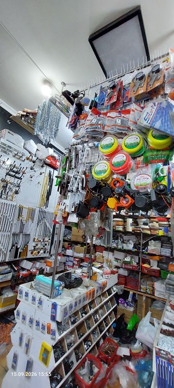Угол магазина с фурнитурой: леска для триммера в катушках, головки триммеров, мебельные ручки и крючки, стойка с ячейками мелкой фурнитуры и колёсиков, кромочная лента, винты и шурупы в корзинах