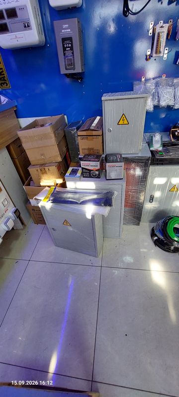 Стена со стабилизаторами напряжения Nura Electric, металлические электрощиты в плёнке на полу, коробки, кабельные стяжки, бухты кабеля