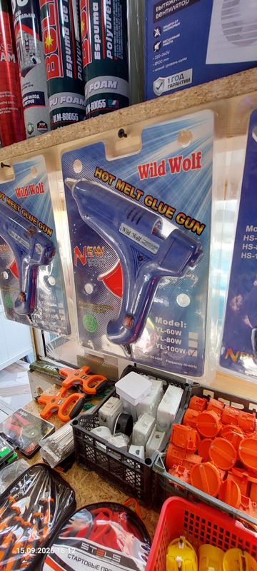 Клеевой пистолет Wild Wolf на блистере (отмечена модель YL-100W), сверху монтажная пена, вытяжной вентилятор; внизу корзины с распределительными коробками и подрозетниками