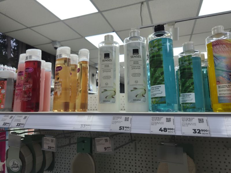 Полка с гелями для душа Camay и Avon Senses, под ней на крючках мочалки с ценниками