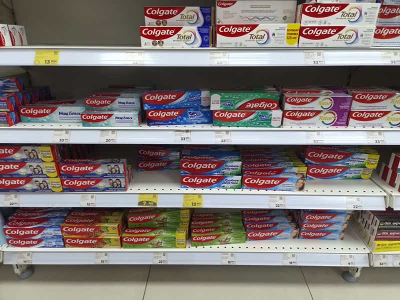 Стеллаж с зубными пастами Colgate, ценники белые и жёлтые