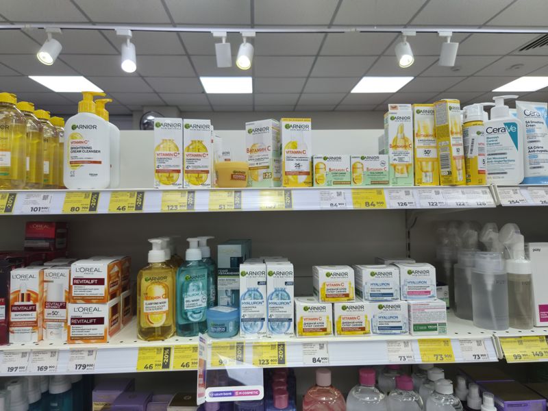 Полки с косметикой Garnier, L'Oreal, CeraVe с витамином С; белые и жёлтые ценники, часть со скидкой 20-30%