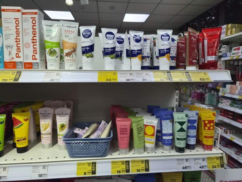 Полки с кремами для рук Compliment, Nivea, Avon, Garnier и Dzintars, ценники белые и жёлтые со скидкой