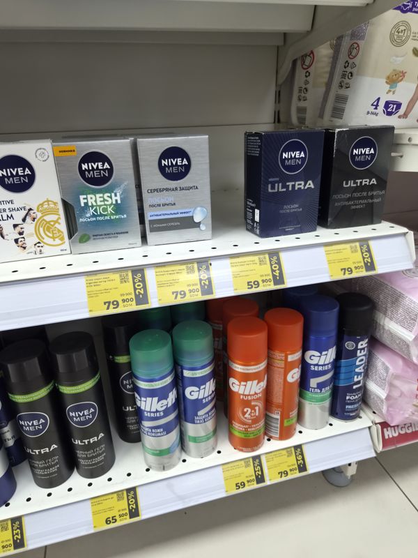 Полки с лосьонами, бальзамами и гелями для бритья Nivea Men и Gillette, жёлтые ценники, снимок под углом