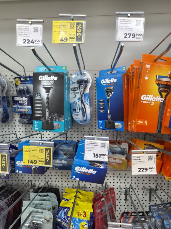 Стенд на крючках с бритвенными станками и кассетами Gillette, Schick, белые ценники и жёлтые со скидкой 36-37%