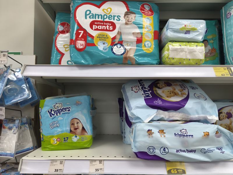 Полки с подгузниками Pampers, Kippers и Evy Baby и детскими сосками Canpol babies, ценники на планках: белые и жёлтые
