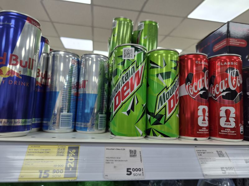 Полка с энергетиками Red Bull, Mountain Dew и Coca-Cola в банках, жёлтый ценник со скидкой и белые
