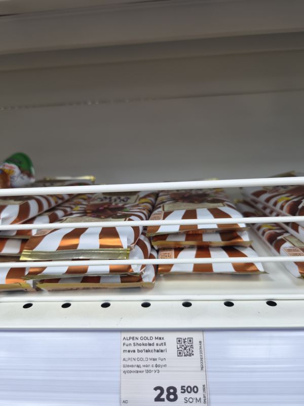 Плитки шоколада Alpen Gold Max Fun на полке за решёткой, белый ценник на ценникодержателе