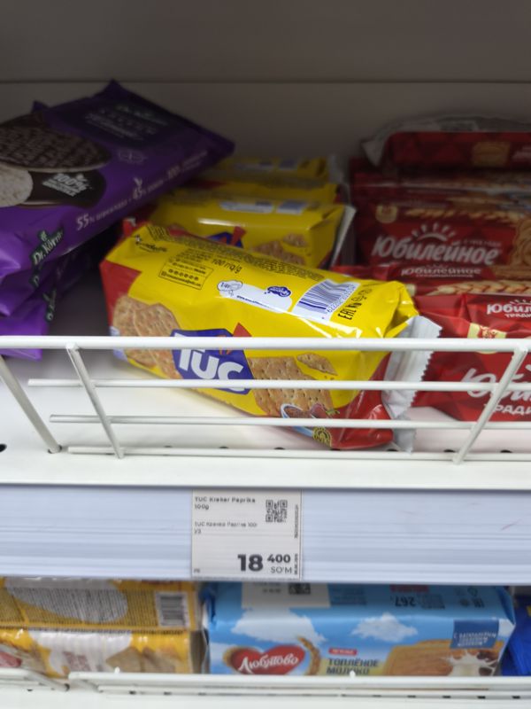 Крекеры Tuc и печенье Юбилейное на полке за решёткой, белый ценник на ценникодержателе