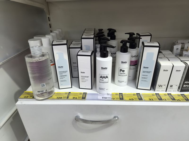 Полка Likato Professional над белым ящиком, ценники жёлтые со скидками и белые, кадр размыт