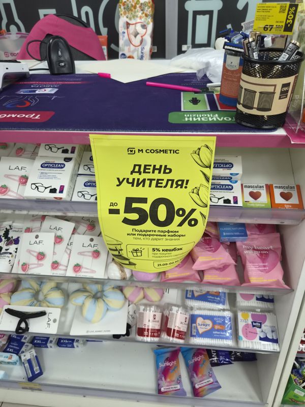 Прикассовая зона с плакатом «День учителя! до -50%» и стеллажами с заколками, салфетками, ватными палочками