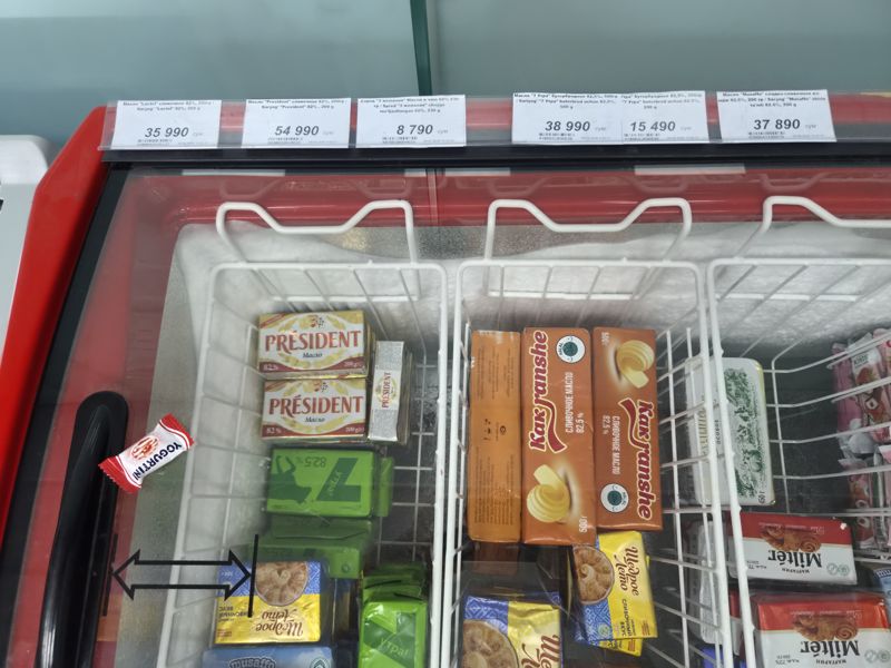 Морозильный ларь со сливочным маслом и спредами; верхний ряд ценников на поручне ларя