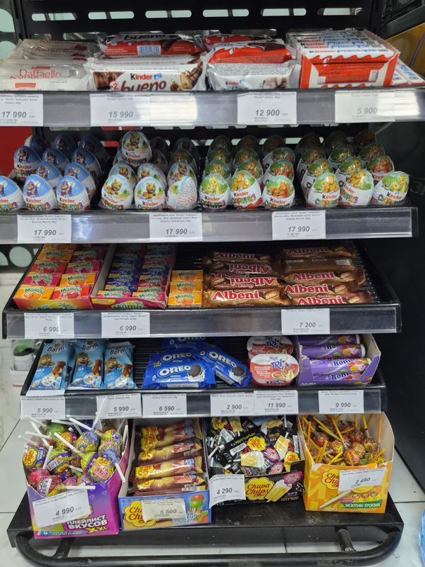 Прикассовая витрина со сладостями: Kinder, Raffaello, Mamba, Albeni, Barni, Oreo, Bonibon, леденцы Chupa Chups, белые ценники