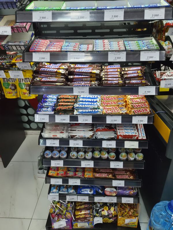 Прикассовая витрина со жвачкой Orbit, батончиками Snickers, Mars, Twix, Kinder, конфетами Mamba, печеньем и леденцами Chupa Chups, белые ценники
