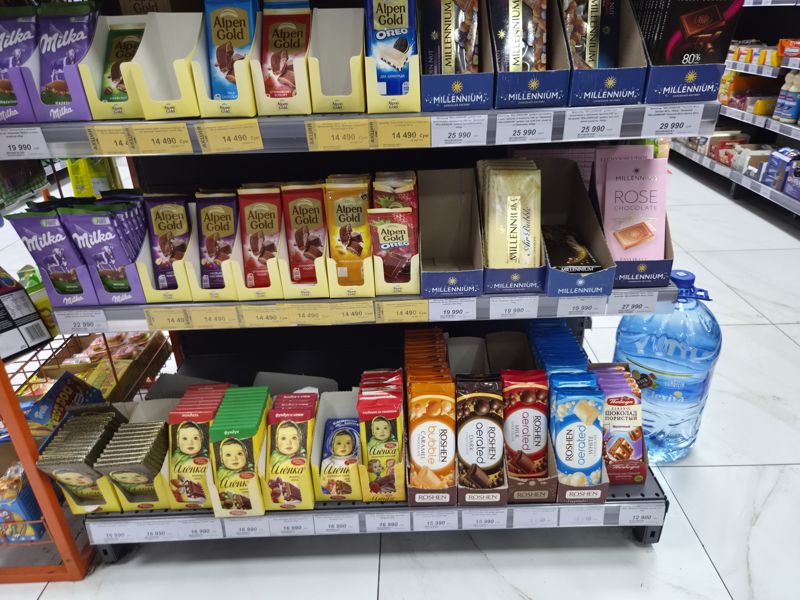 Полка с плиточным шоколадом в супермаркете: Milka, Alpen Gold (жёлтые акционные ценники), Millennium, Аленка, Roshen, Победа