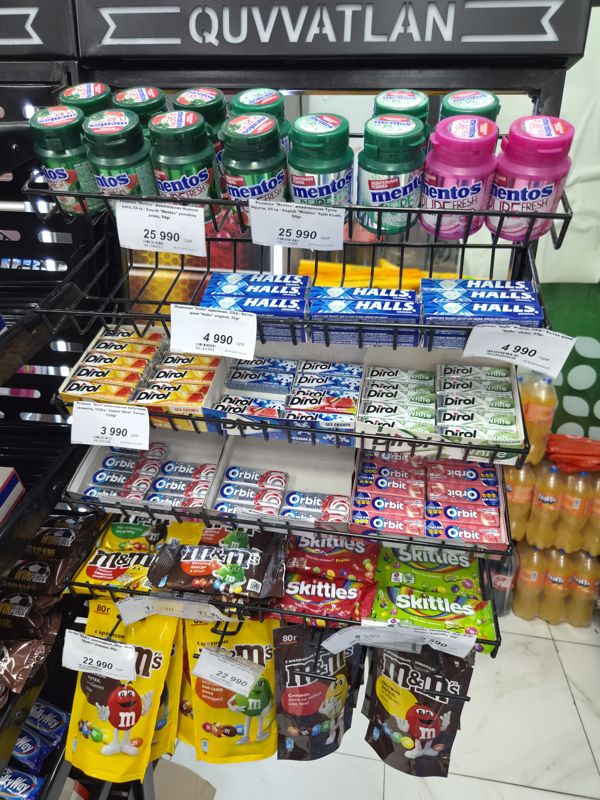 Стеллаж у кассы: жевательная резинка Mentos, Dirol, леденцы Halls, драже M&M's и Skittles