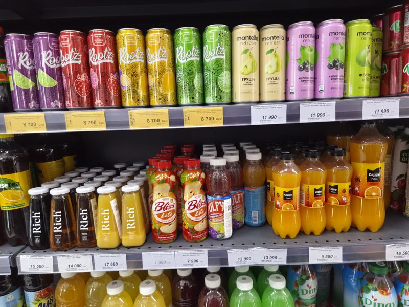 Холодильная витрина с напитками в супермаркете Олма: банки Rootz и Montella Refresh, соки Rich, Bliss lite, Pulpy и Cappy Pulpy; белые и жёлтые акционные ценники