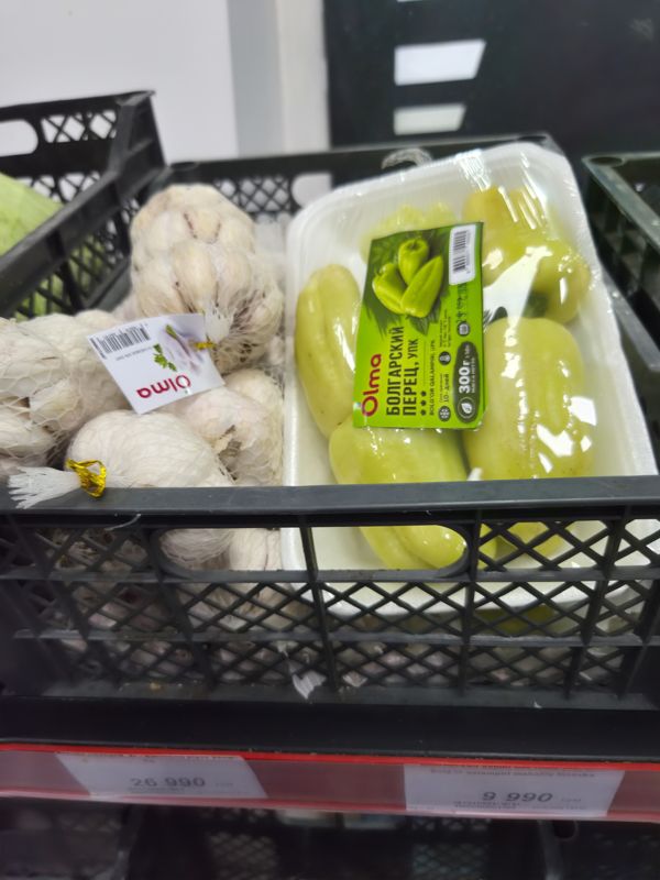 Ящик с чесноком Olma в сетках и упаковка болгарского перца Olma 300 г; два ценника на полке