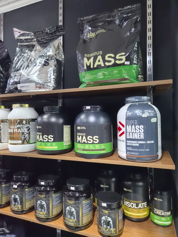 Стеллаж с гейнерами и протеинами: Serious Mass, Super Mass Gainer, Unkrowned King