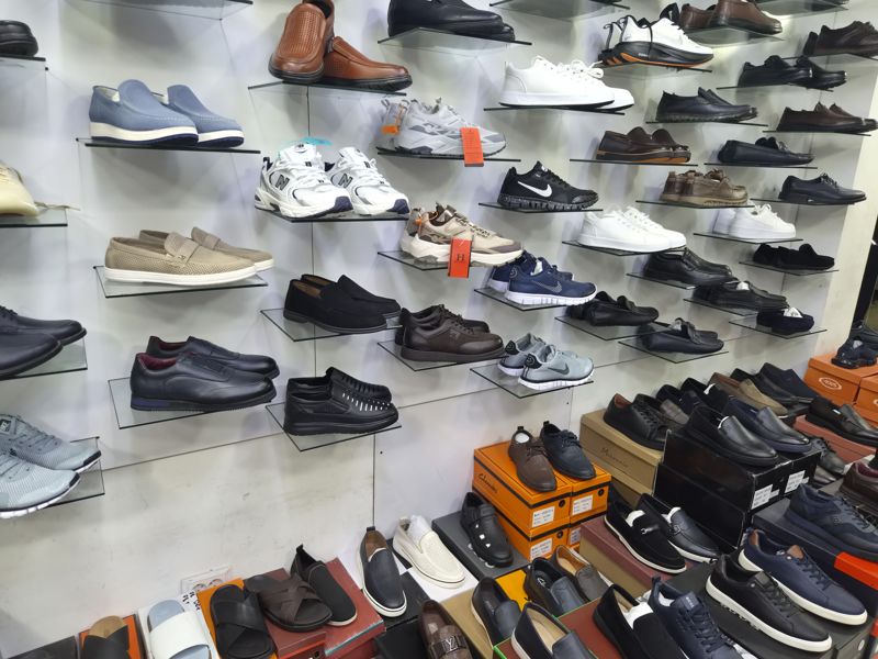 Стена мужской обуви и коробки с туфлями: мокасины, кроссовки New Balance, Hilanza, Nike