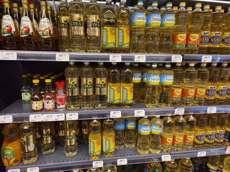 Подсолнечное масло и уксус на полках, белые ценники; ценники масла повторяются на трёх полках
