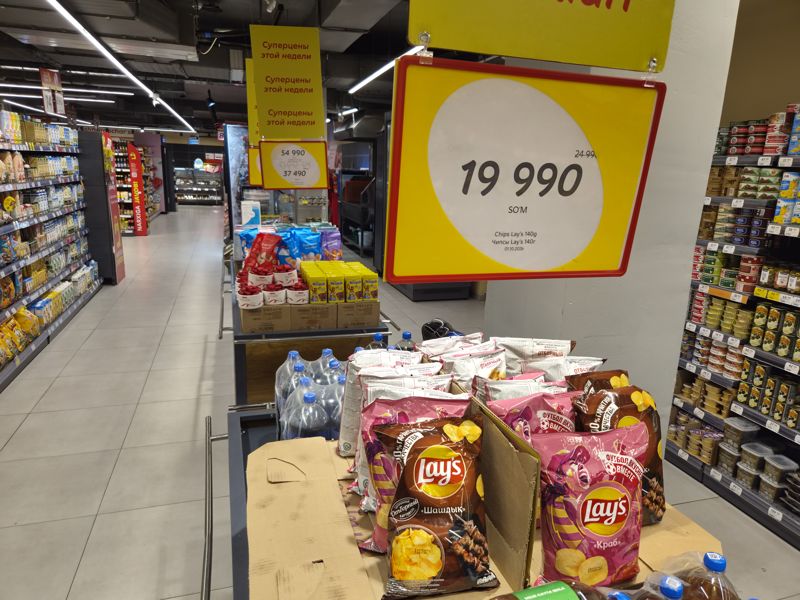 Витрина с чипсами Lay's и газировкой, над ней жёлтые карточки: Lay's 140 г, Raffaello и Nesquik