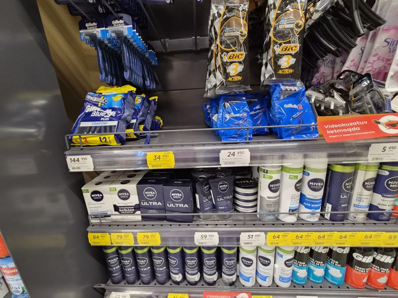 Одноразовые станки Gillette и BIC, средства для бритья и после бритья Nivea Men на полках; белые и жёлтые ценники
