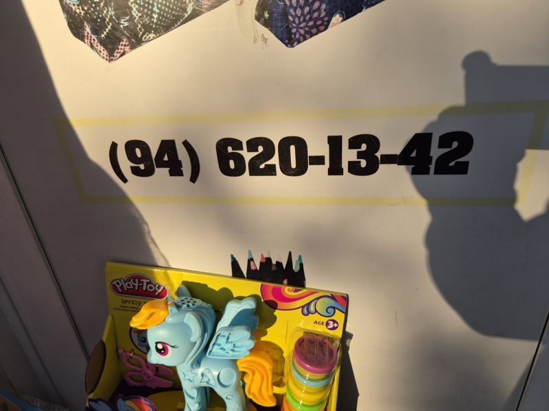 Стена у входа с номером телефона, внизу коробка Play-Toy Lovely Horse, рядом цветные карандаши, вверху рюкзаки