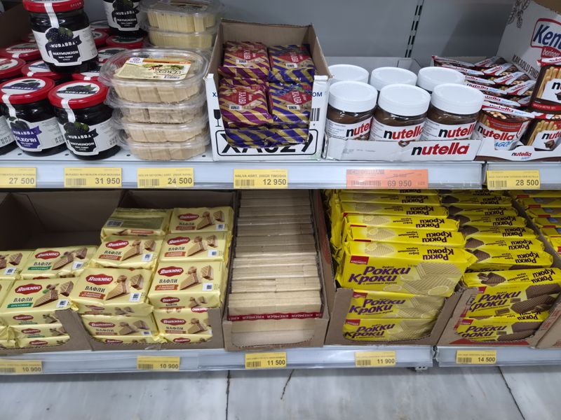 Havas: халва, варенье, шоколадная паста Nutella и вафли Яшкино и Krember Рокки Кроки на двух полках; жёлтые ценники и оранжевый Chegirma