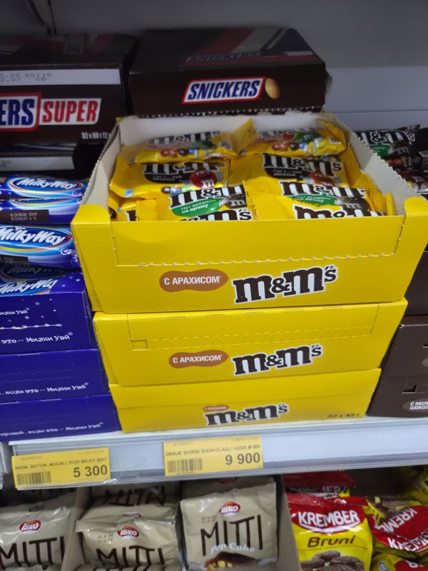 Havas: жёлтые коробки драже M&M's с арахисом (32 × 45 г), слева Milky Way, сверху Snickers, снизу печенье Isko Miti и кексы Krember Bruni