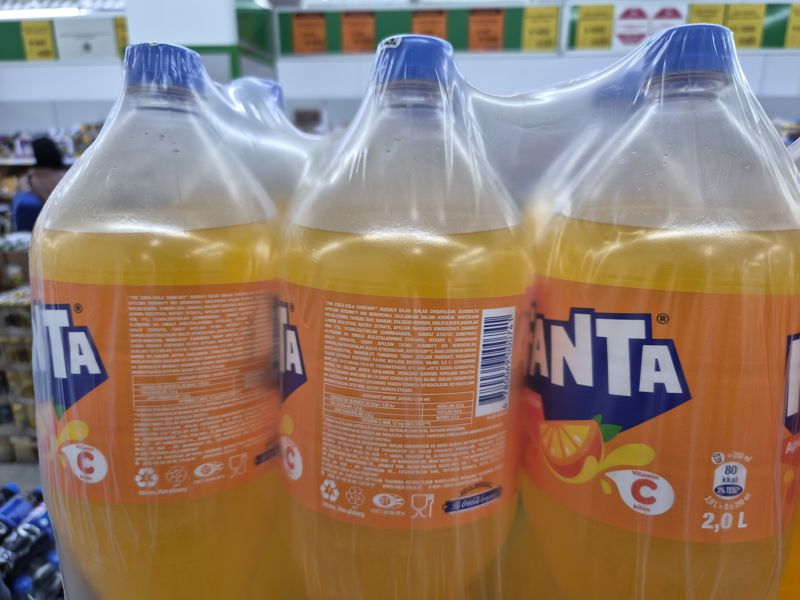 Упаковки Fanta апельсиновая 2 л в плёнке, на задней этикетке штрихкод, вверху на планке жёлтые и оранжевые ценники