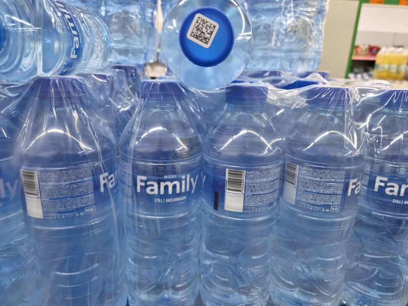 Упаковки воды Family негазированной 0,5 л в плёнке, на задней этикетке штрихкод; одна бутылка стоит вверх дном — на крышке код маркировки