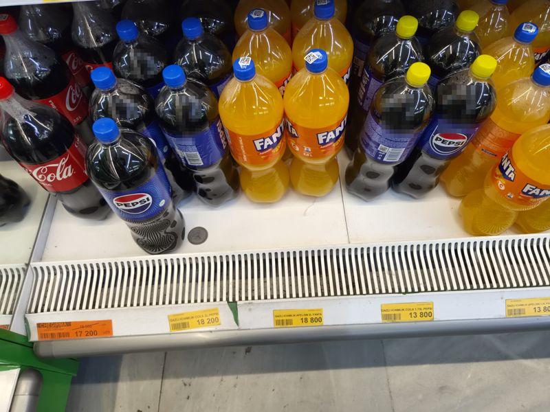 Напольная полка с газировкой 2 л: Coca-Cola, Pepsi, Fanta в бутылках, под ними ценники; слева оранжевый ценник «Chegirma»