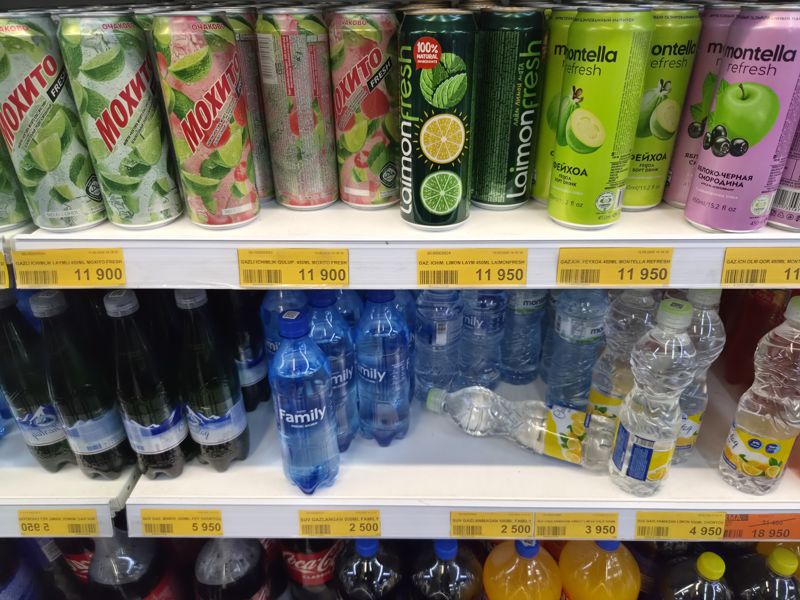 Две полки напитков: сверху банки Moxito Fresh, Laimonfresh и Montella Refresh, ниже вода Chortoq, Family и другие, внизу газировка; под полками жёлтые ценники