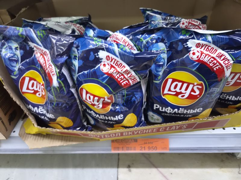 Полка с чипсами Lay's «Рифлёные сметана и лук» в картонном коробе, оранжевый ценник Chegirma