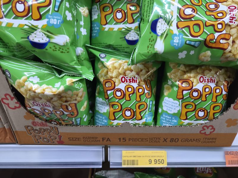 Полка с кукурузными снеками Oishi Poppy Pop «Сметана и лук» 80 г; на жёлтом ценнике — чипсы Grizzly сметана и лук 55 г